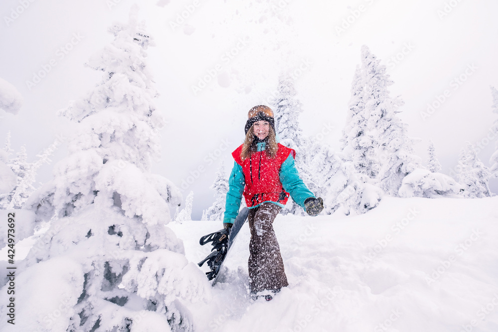 Happy snowboarder woman holding snowboard during Powder Day, winter holiday in ski resort