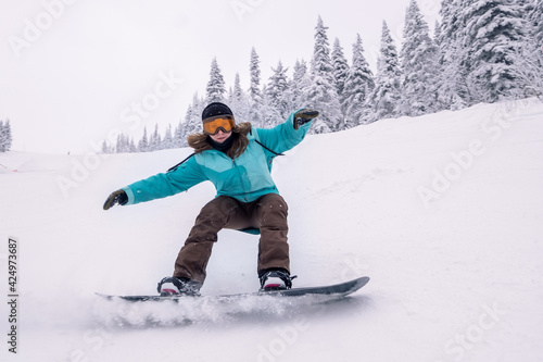 Snowboarder female riding on winter snow cowered slop on snowboard. Powder Day, winter holiday in ski resort