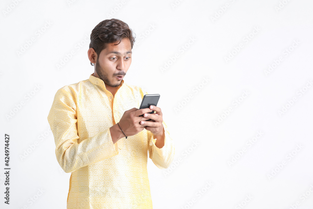 Young indian man in tradition wear and using smartphone on white background. Young indian man in tradition wear and using smartphone on white background.