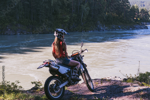 Fototapeta Naklejka Na Ścianę i Meble -  Female enduro biker with motorcycle on the cliff near mountains river