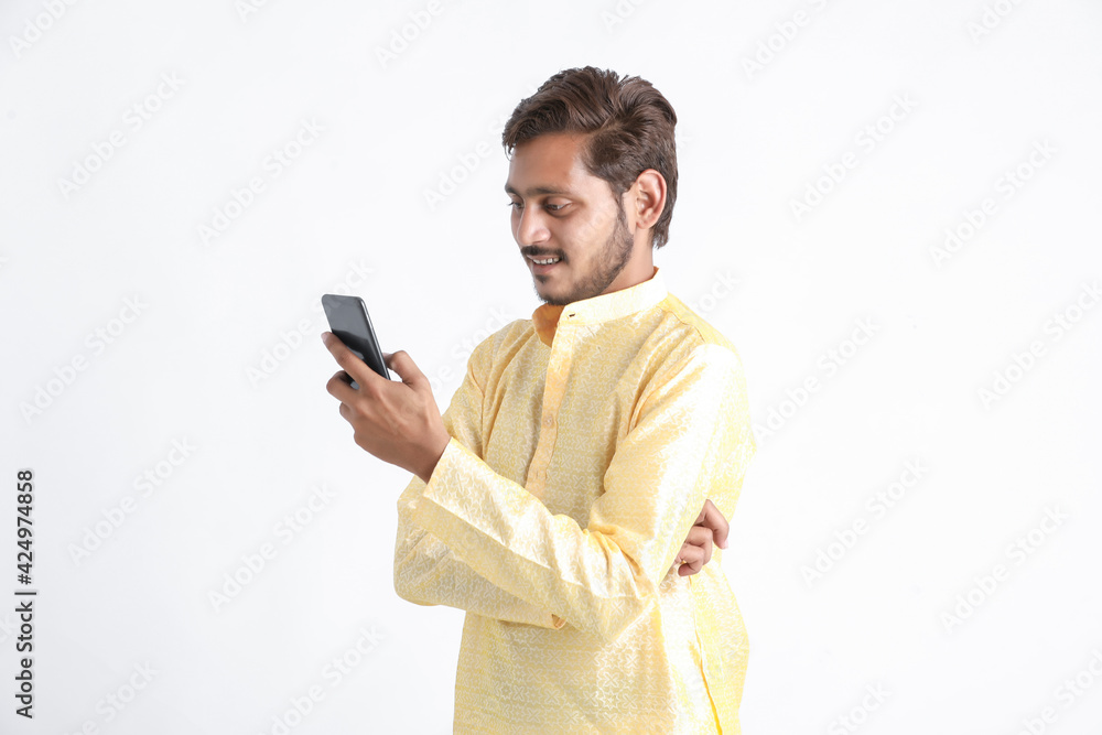 Young indian man in tradition wear and using smartphone on white background. Young indian man in tradition wear and using smartphone on white background.
