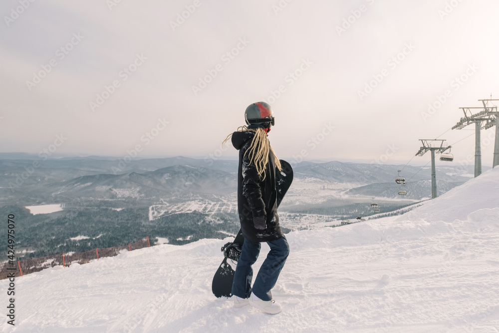 Snowboarder female enjoying the ski resort. Mountain landscape view, ski lift. Sheregesh. Russia