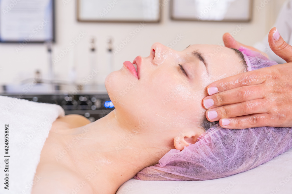 Woman in a spa salon getting face massage for facial care. Beautician makes a massage of the face with a moisturizing mask on a face. Beauty treatment concept. Woman in a spa salon getting face massage for facial care. Beautician makes a massage of the face with a moisturizing mask on a face. Beauty treatment concept.