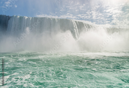 Horseshoe Falls  a part of Niagara Falls  with a sun shining through a tall dense cloud