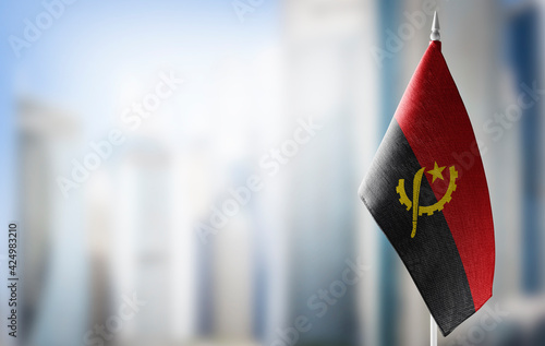 A small flag of Angola on the background of a blurred background
