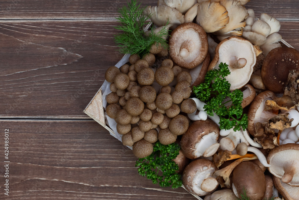 Variety of uncooked wild forest mushrooms in a wood box on wooden old board. Variety of uncooked wild forest mushrooms in a wood box on wooden old board.