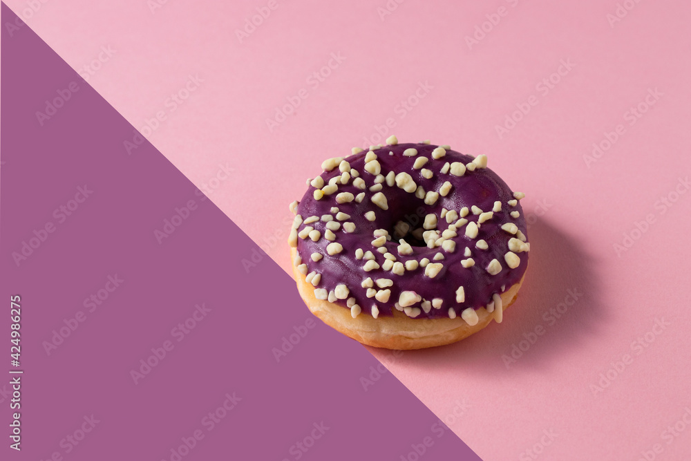 Donut with blueberry glaze and nuts on two colour background .Sweet minimalist food image. Modern concept. Donut with blueberry glaze and nuts on two colour background .Sweet minimalist food image. Modern concept.