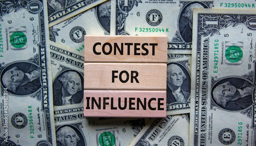 Contest for influence symbol. Wooden blocks with words 'Contest for influence'. Beautiful background from dollar bills. Business, contest for influence concept, copy space.