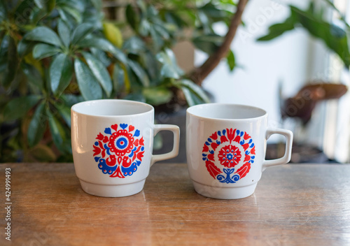 Mid-century modern porcelain cups with retro pattern on a wooden tablewith plants in the background