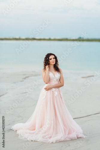 girl in a pink dress are walking along the white sand © omelnickiy