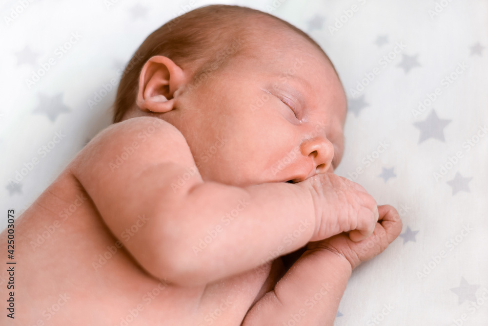 Closeup portrait of Newborn baby sleeping on white blanket. Soft focus. A one weeks old infant is sleeping tightly on her side in bed. 10 days old child. Closeup portrait of Newborn baby sleeping on white blanket. Soft focus. A one weeks old infant is sleeping tightly on her side in bed. 10 days old child.