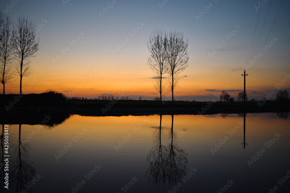 incredible sunset on the Muzza river, lights, colors and reflections surround this breathtaking landscape