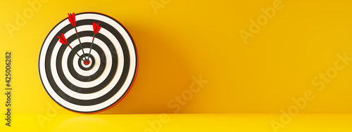 Zielscheibe mit 3 Pfeilen vor gelber Wand