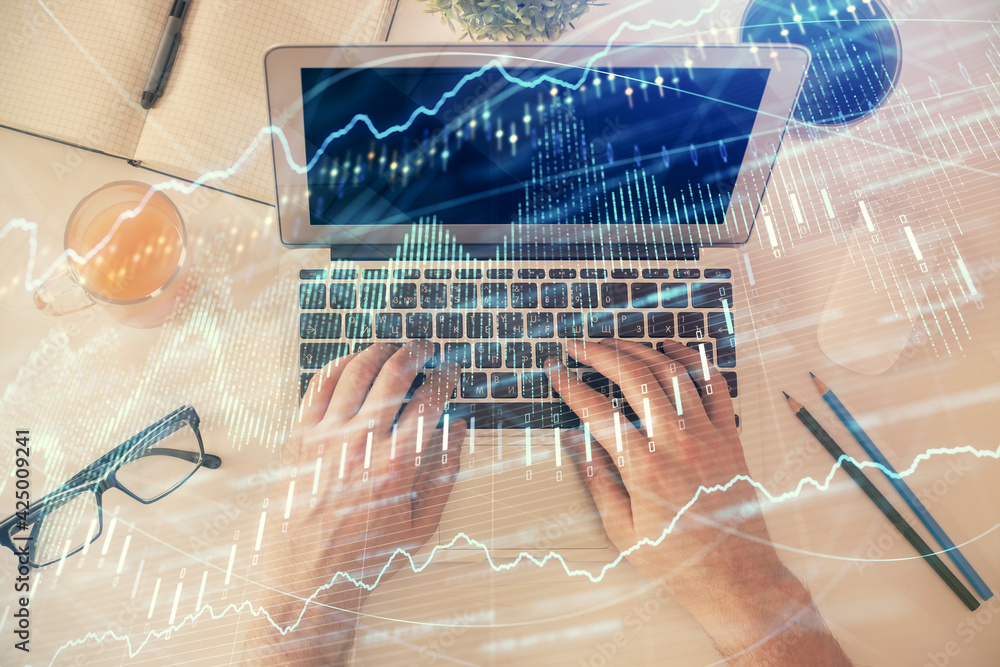 Double exposure of man's hands typing over laptop keyboard and forex chart hologram drawing. Top view. Financial markets concept. Double exposure of man's hands typing over laptop keyboard and forex chart hologram drawing. Top view. Financial markets concept.
