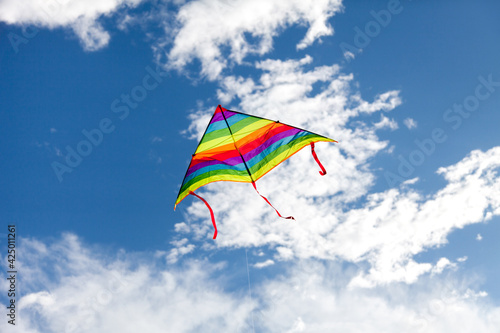 Kite flying in blue sky. Rainbow symbol