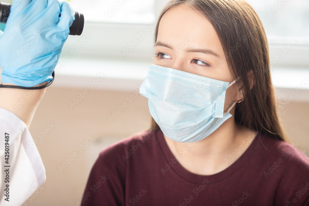 Medical check, eye examination in adolescents, the doctor shines a flashlight in the eye of a young girl Medical check, eye examination in adolescents, the doctor shines a flashlight in the eye of a young girl