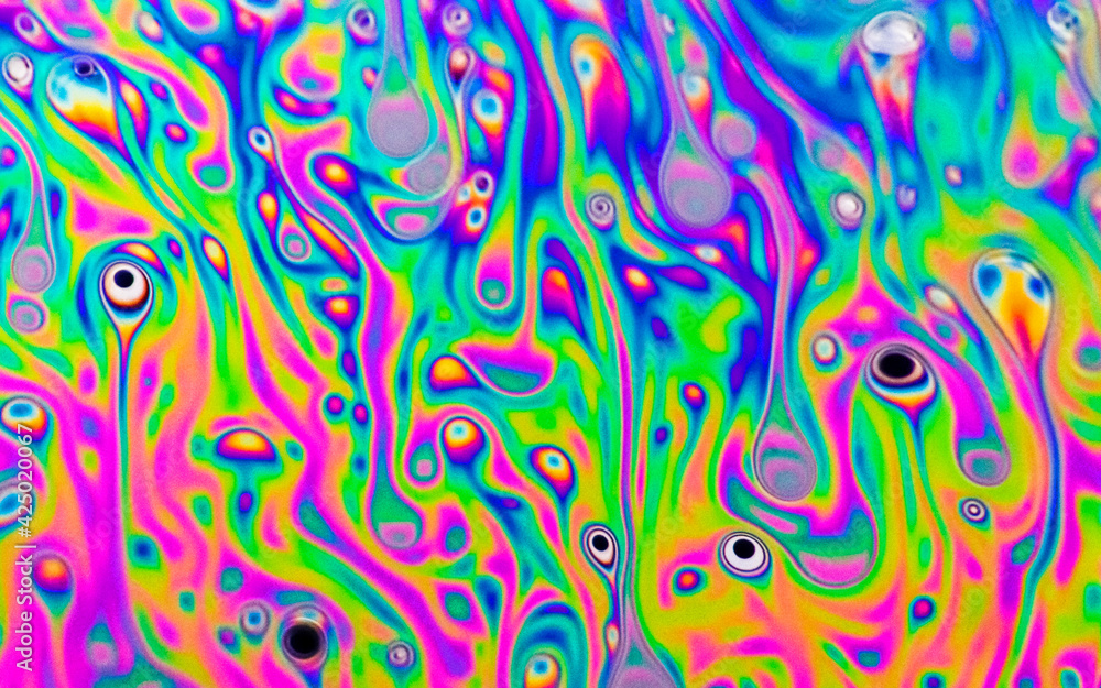 Colourful macro photograph of soap bubble film with rainbow colours melting into one another