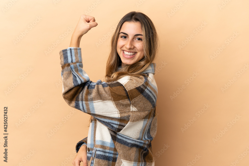 Young caucasian woman isolated on beige background doing strong gesture Young caucasian woman isolated on beige background doing strong gesture