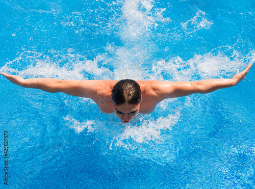 Athletic man swimming in pool butterfly style