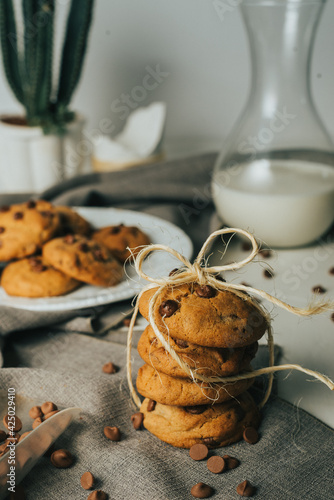  Chocolate chip Cookies on white table concept shot with milk, green cactus grey napkin