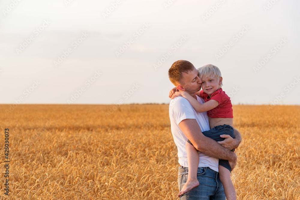 Young son hugging his father. Happy dad and child on .. background of wheat field Young son hugging his father. Happy dad and child on .. background of wheat field
