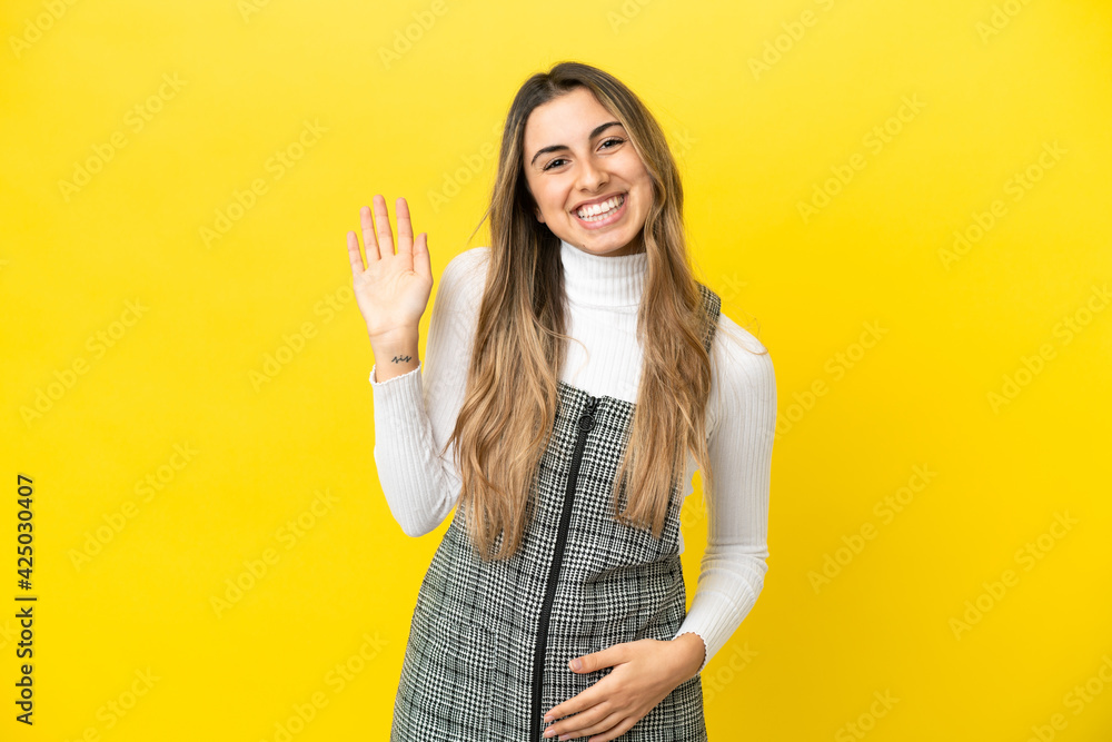Young caucasian woman isolated on yellow background saluting with hand with happy expression Young caucasian woman isolated on yellow background saluting with hand with happy expression