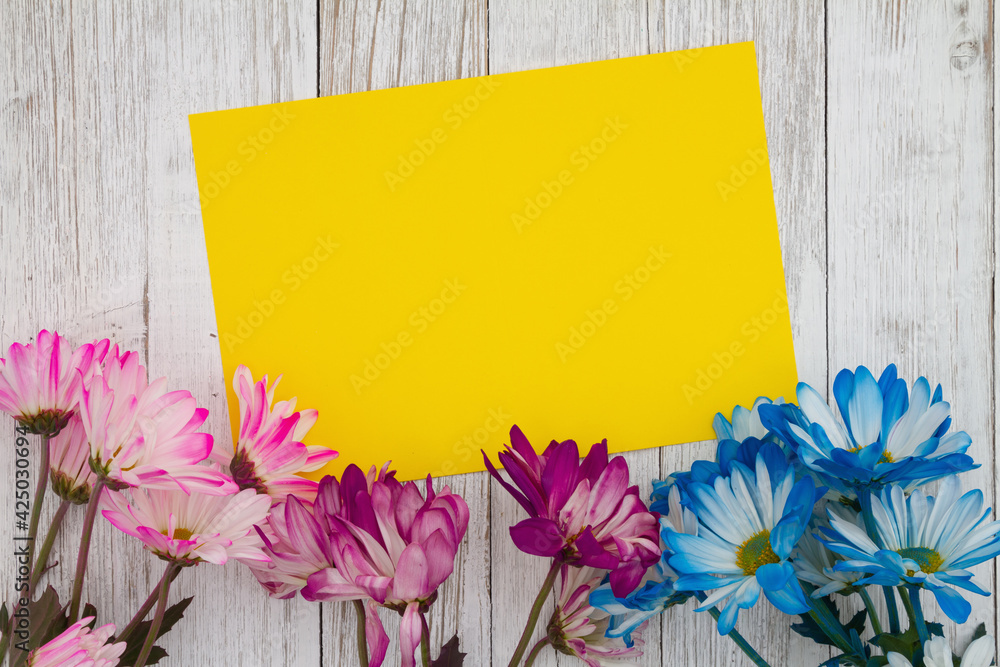 Fototapeta premium Blank yellow card with blue and pink daisies bunch of flowers