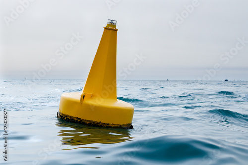 Yellow navigational sea buoy in the waves in the marina near Dubai photo