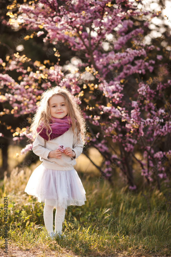 Pretty little child girl 4-5 year old with flowers over blooming nature background close up. Spring season. Childhood. Pretty little child girl 4-5 year old with flowers over blooming nature background close up. Spring season. Childhood.