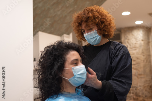 Hairdresser with facemask working in pandemic new normal