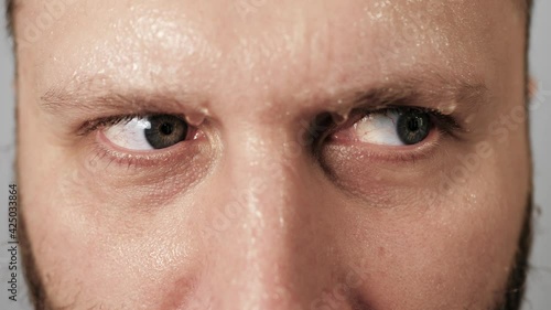 Panic, fear, horror, paranoia, nervousness concept. Agitated man looks around in panic, beads of sweat running down his face and dripping from his forehead and eyebrows. Close-up photo