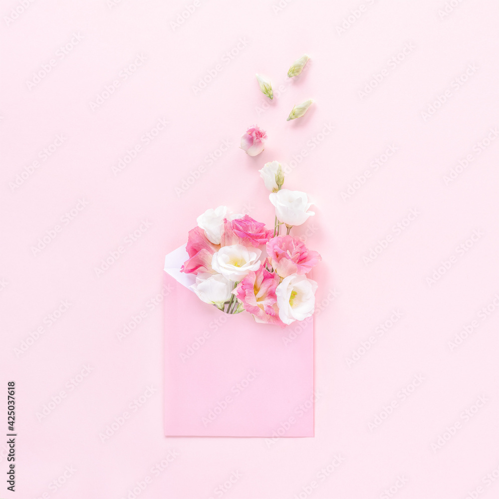 Open pink envelope full of spring flowers on pink background. Top view. Greeting card with eustoma flowers. Concept of spring.