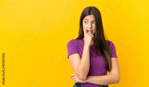 Teenager Brazilian girl over isolated yellow background nervous and scared © luismolinero