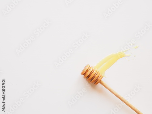 Honey dripping from a wooden honey dipper isolated on white with copy space