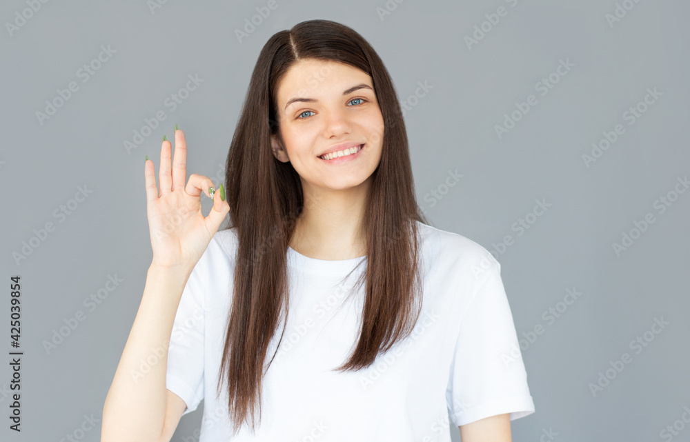 Cheerful funny cute girl gesturing ok isolated on gray background Cheerful funny cute girl gesturing ok isolated on gray background