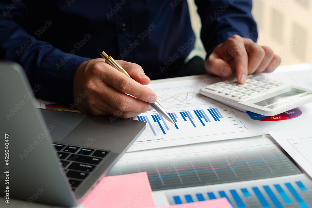 businessman working on desk office with using a calculator to calculate the numbers, finance accounting concept