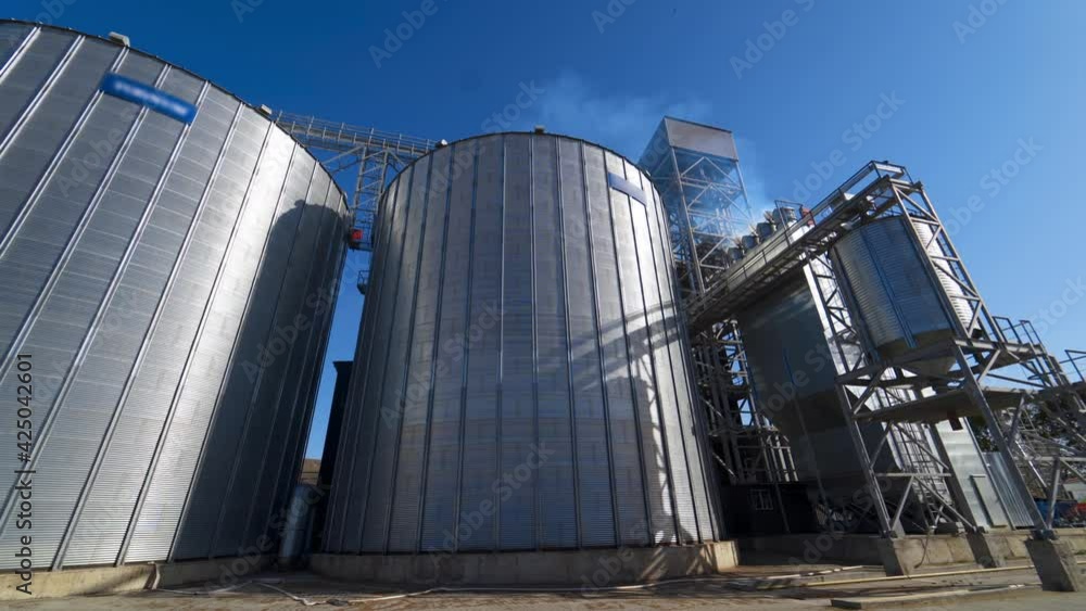 Exterior of grain elevators on field. Large granary of a modern industrial plant for agriculture. Industrial complex for storage crop. Exterior of grain elevators on field. Large granary of a modern industrial plant for agriculture. Industrial complex for storage crop.