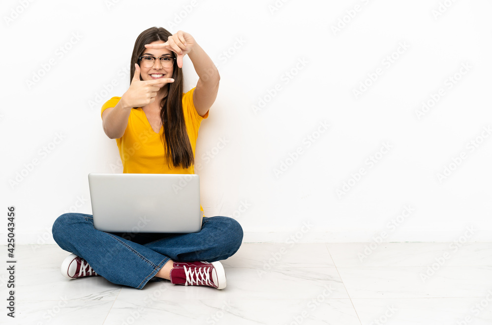 Young woman with a laptop sitting on the floor focusing face. Framing symbol Young woman with a laptop sitting on the floor focusing face. Framing symbol