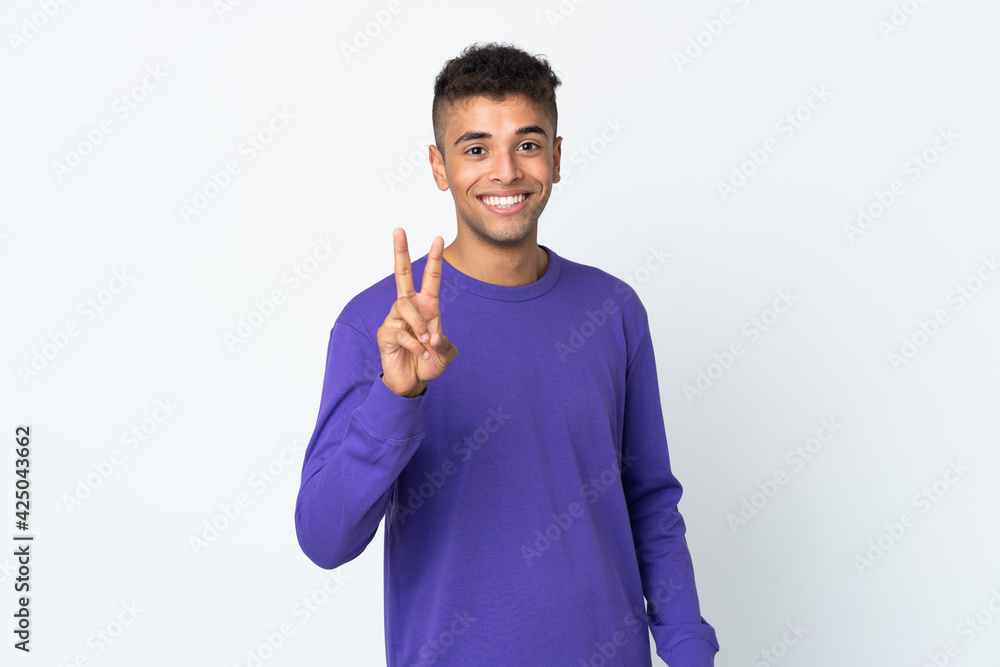Young brazilian man isolated on white background smiling and showing victory sign Young brazilian man isolated on white background smiling and showing victory sign