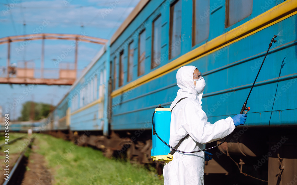 Man in Hazmat suit, protective gloves and goggles use sprayer equipment disinfect a train. Covid-2019. Man in Hazmat suit, protective gloves and goggles use sprayer equipment disinfect a train. Covid-2019.