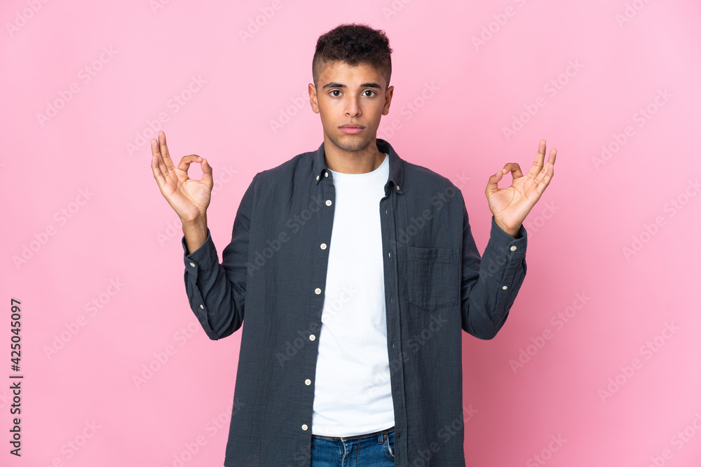Young Brazilian man isolated on pink background in zen pose Young Brazilian man isolated on pink background in zen pose