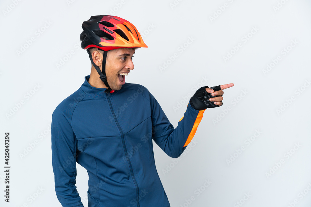Young cyclist Brazilian man isolated on white background pointing finger to the side and presenting a product - obrazy, fototapety, plakaty 