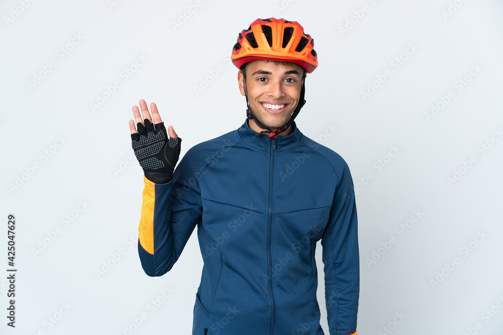 Young cyclist Brazilian man isolated on white background saluting with hand with happy expression - obrazy, fototapety, plakaty 