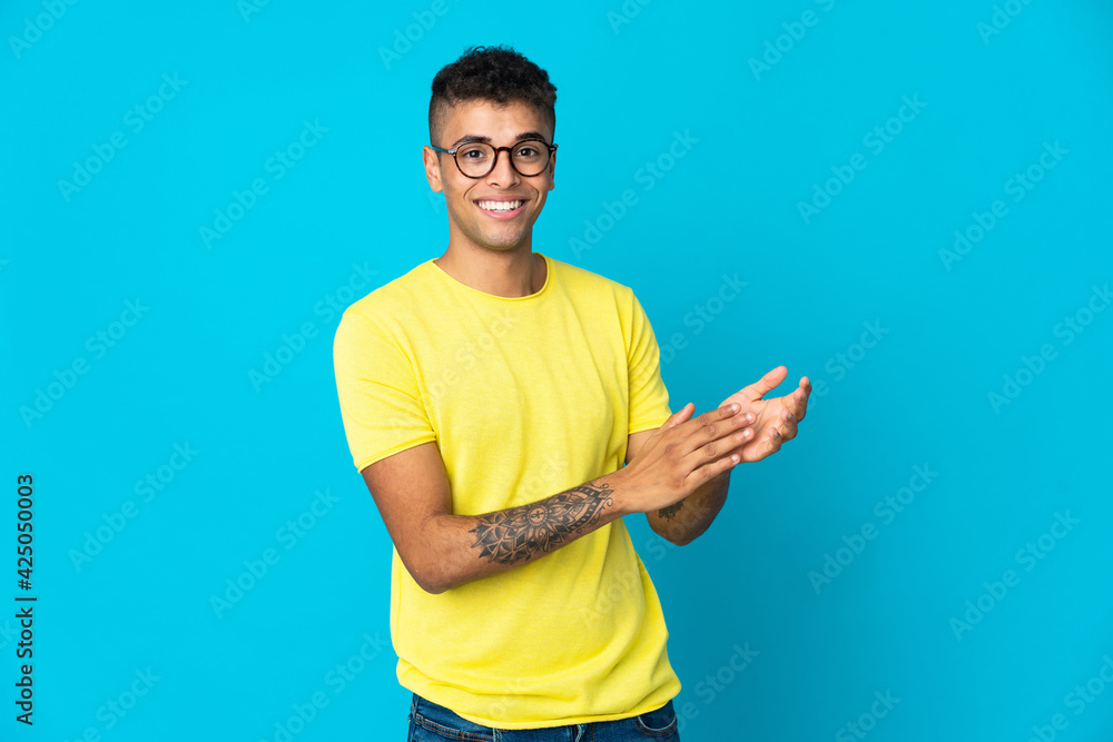 Young Brazilian man isolated on blue background applauding Young Brazilian man isolated on blue background applauding