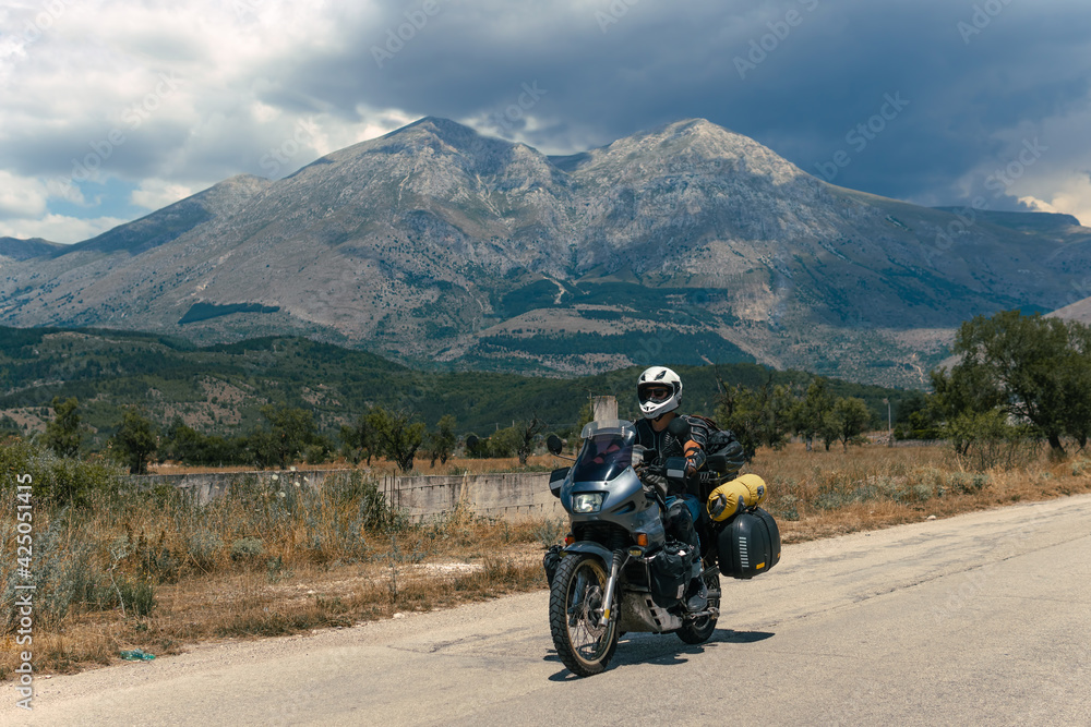 Moto Biker riding on road, drive a motorcycle, summer adventure, travel to Europe, active lifestyle, vacation concept Magliano de Marsi, on background Riserva Naturale Orientata Monte Velino Moto Biker riding on road, drive a motorcycle, summer adventure, travel to Europe, active lifestyle, vacation concept Magliano de Marsi, on background Riserva Naturale Orientata Monte Velino