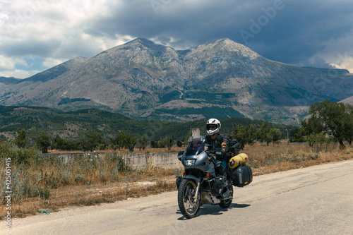 Moto Biker riding on road, drive a motorcycle, summer adventure, travel to Europe, active lifestyle, vacation concept Magliano de Marsi, on background Riserva Naturale Orientata Monte Velino