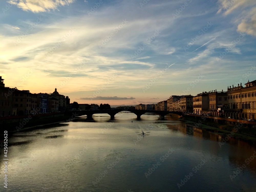 Sunset view from the Ponte Santa Trinita to Ponte alla Carraia in Florence. Reflection. Italy. Boat, sunset, light, twilight, sky. Arno river, bridge. 