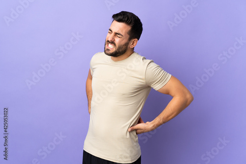 Young handsome man with beard over isolated background suffering from backache for having made an effort