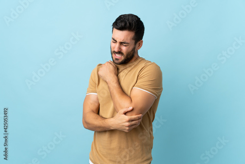 Young handsome man with beard over isolated background with pain in elbow