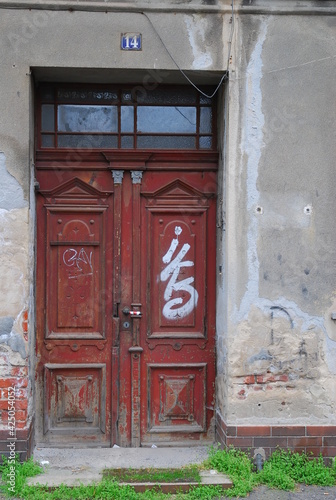 Red wooden old door with graffiti on an abandoned house © Gregor